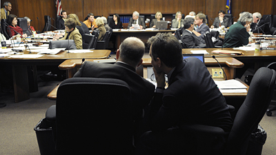Finance Commissioner Tom Hanson, left, and State Budget Director Jim Schowalter confer as a member of the House Finance Committee makes a comment during the March 10 presentation of the governor