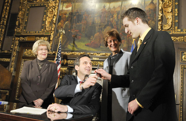 Gov. Tim Pawlenty presents the pen he used to sign into law a bill lowering the age for which a person can donate blood to Joe Gibson, the Blooming Prairie teenager who inspired the legislation. Also at the March 18 bill signing are the bills sponsors, Rep. Patti Fritz, left, and Sen. Kathy Sheran, center right.