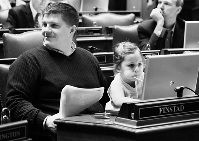Rep. Brad Finstad holds his daughter, Greta, as she enjoys a sucker and the computer at his desk in the House Chamber. (Photo by Sarah Stacke)
