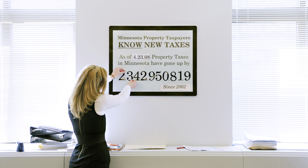 Leesa Paalman, a University of Minnesota intern for Rep. Paul Marquart, updates a sign outside Marquart�s office April 23 showing the increase in the state�s property taxes since 2002. Marquart chairs the House Property Tax Relief and Local Sales Tax Division. (Photo by Tom Olmscheid)