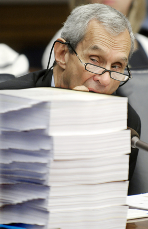 While listening to testimony May 21, Rep. Ron Erhardt, a member of the Joint Committee to Investigate the Bridge Collapse, peers around five volumes of appendices to an investigation on the bridge collapse. (Photo by Tom Olmscheid)