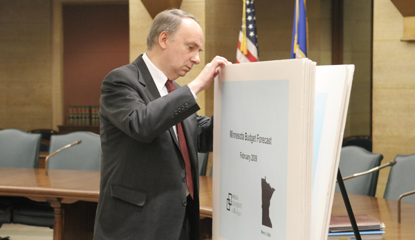 State Economist Tom Stinson takes a peek at the charts and graphs that illustrate the state budget forecast prior to a March 3 news conference. (Photo by Tom Olmscheid)