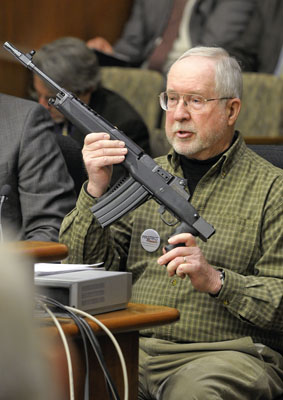 Jerry Dhennin, retired sheriff’s deputy, displays an assault rifle to the House Crime Victims/Criminal Records Division March 5 during his testimony supporting a bill that would require a background check for transfer of a firearm at a gun show. (Photo by Andrew VonBank)