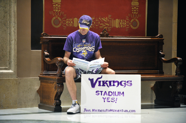 Larry Spooner sits on a bench outside the House Chamber and reads a handout promoting a new stadium for the Minnesota Vikings. He was waiting to testify May 4 before the House Local Government Division, but time constraints prohibited public testimony. (Photo by Tom Olmscheid)
