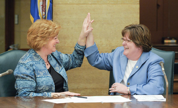 In a bi-partisan gesture, Rep. Marsha Swails, left, and Rep. Carol McFarlane, right, give each other a �high five� after the conclusion of a May 3 conference committee that meant the completion of a bill the two co-authored that would establish a collaborative governance council. (Photo by Andrew VonBank)