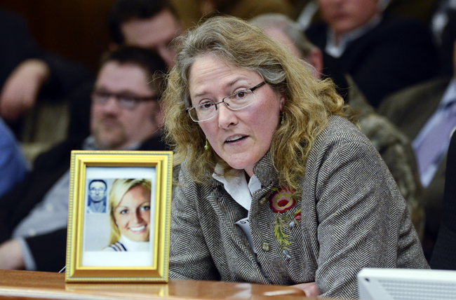 Displaying a photograph of a gun victim and her shooter, Heather Martens, executive director of Protect Minnesota, testifies before a packed House Public Safety and Crime Prevention Policy and Finance Committee April 28 in opposition to a bill that would amend the law on use of force in defense of a persons home. (Photo by Andrew VonBank)