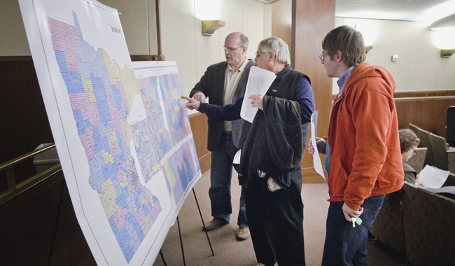 Tim Kinley of Maplewood, from left, Bob Murray of Roseville and Curtis Neff of St. Paul take a look at the proposed legislative district maps prior to a hearing of the House Redistricting Committee May 3. (Photo by Tom Olmscheid)