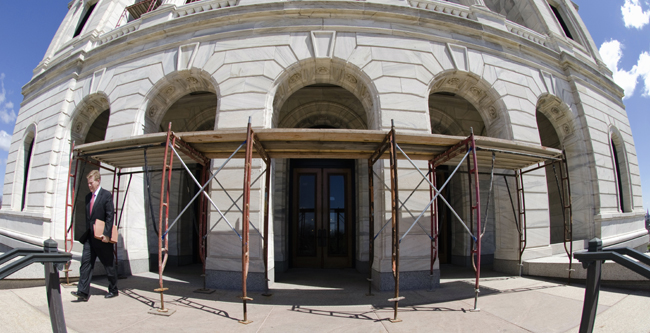 A visitor passes under scaffolding covering the Capitol�s west entrance. Fears of injury caused by deteriorated stonework falling off the marble exterior prompted officials to place protective structures around the building. (Photo by Tom Olmscheid)