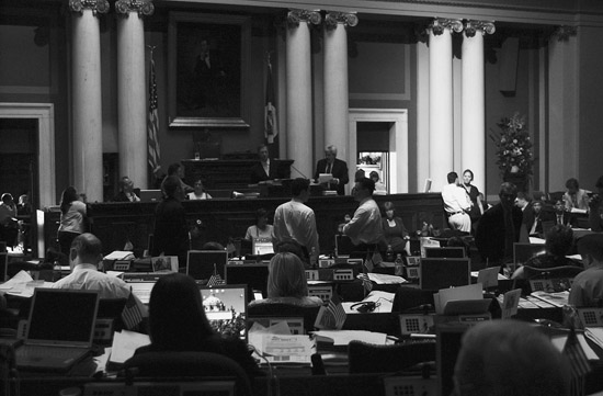 Rep. Karen Klinzing and Shawn M. Peterson, director of majority legislative services, talk in a beam of light shining on the right side of the front desk in the House Chamber during a July 13, 2005 blackout at the Capitol during a special session. (Photo by Tom Olmscheid)