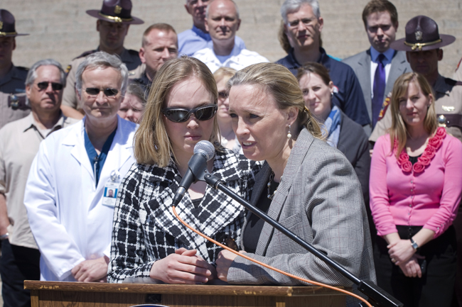Sharon Pearson, right, tells reporters May 17 that her daughter Bethany, left, would not be alive if she had not been wearing her seatbelt when her car was T-boned by a truck. The news conference was held in response to the House’s vote to repeal the primary seatbelt law as part of the omnibus judiciary policy bill passage the previous night. (Photo by Tom Olmscheid)