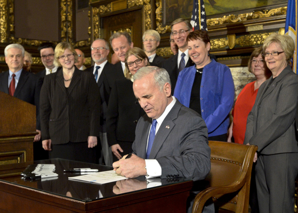 Surrounded by legislators and interested parties, Gov. Mark Dayton signs a bill April 18 that will protect vulnerable adults. (Photo by Andrew VonBank)