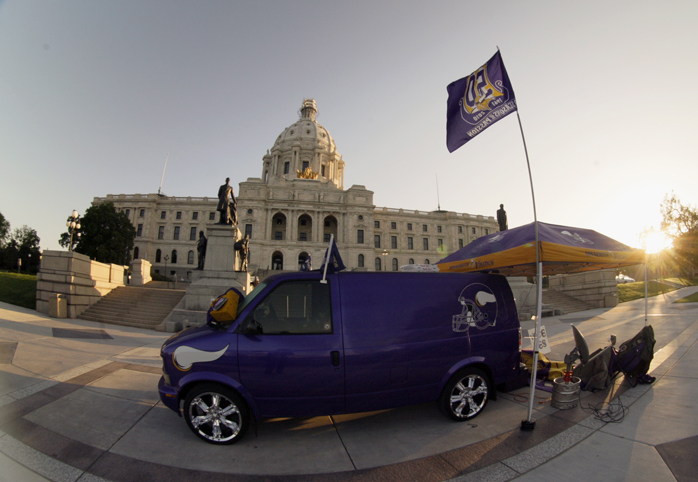 As the sun rises on the Capitol May 10, superfan Larry Spooner is asleep on the ground at the back of the van that had been the headquarters for fans from the Vikings World Order. Spooner has advocated for a new stadium for more than a decade. (Photo by Paul Battaglia)