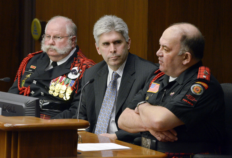 Richard Cady, left, event coordinator for the Minnesota State Fire Service Memorial Pipe Band, and Pipe Major/Director of Music Lynn Ista testify before the House Government Operations and Elections Committee March 9 in support of a bill sponsored by Rep. Joe Atkins, center, that would designate an official state pipe band. (Photo by Andrew VonBank)