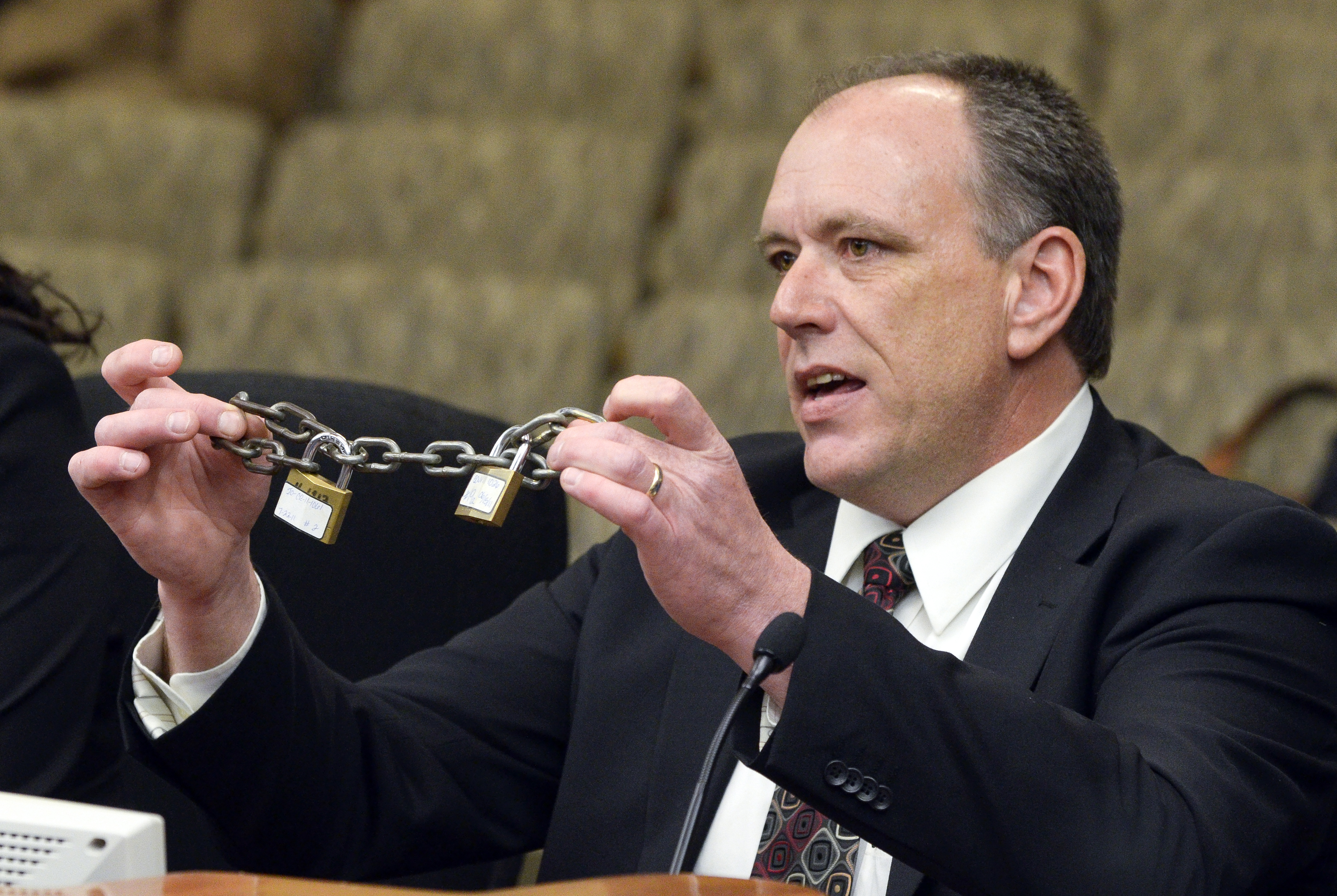 Holding chains that were used to restrain a child, Steve Sandvik, a detective with the Mower County Sheriff’s Office, testifies before the House Judiciary Policy and Finance Committee March 15 in support of a bill that would change the demonstrable harm level in the unreasonable restraint of children. (Photo by Andrew VonBank)